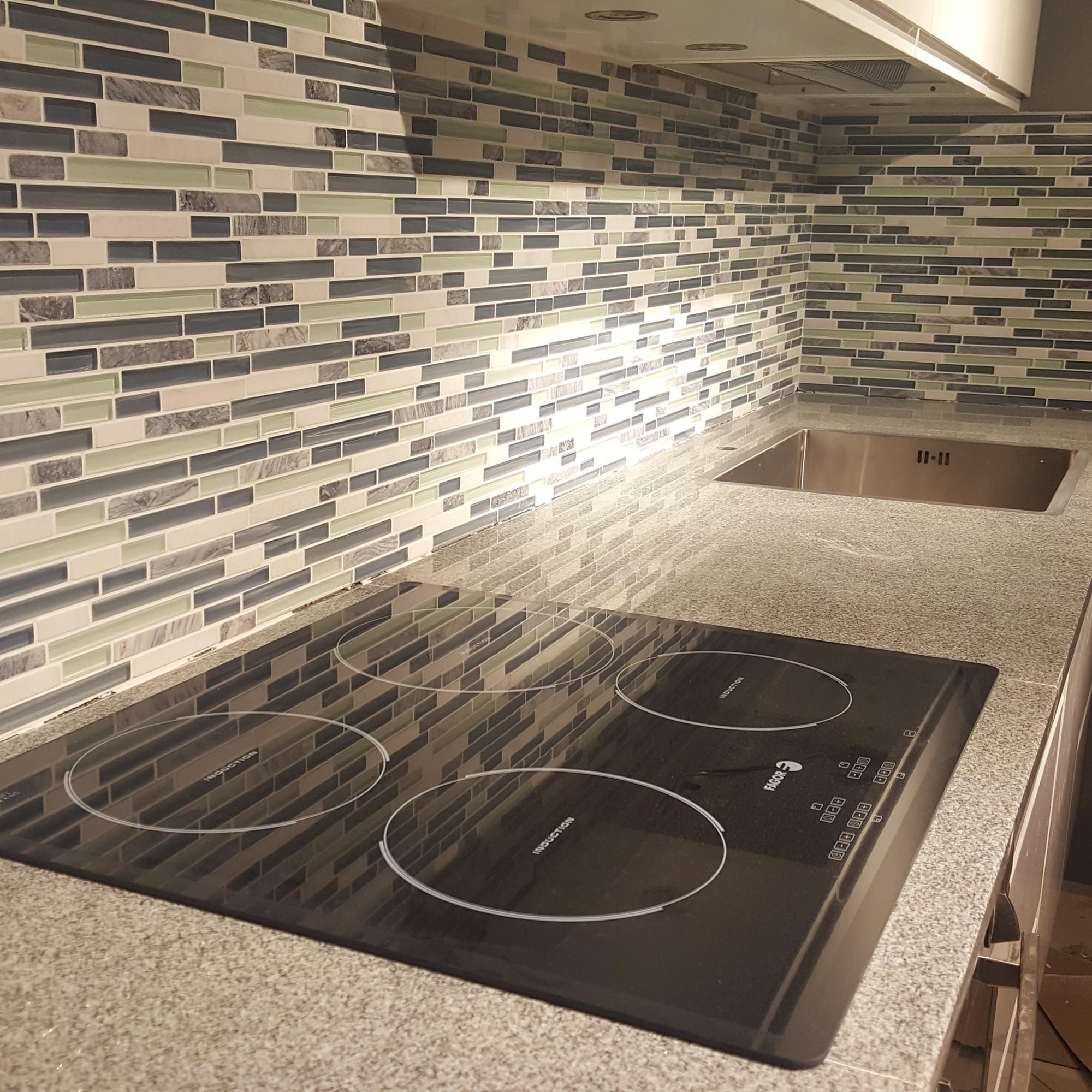 Glass mosaic backsplash by cooktop and sink