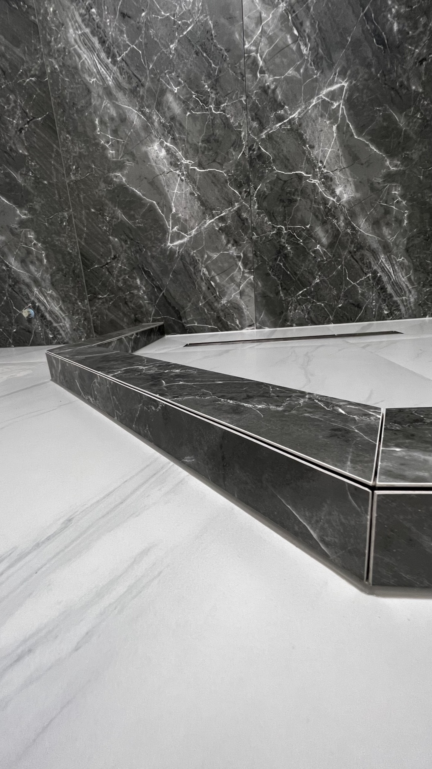 Dark tile shower curb with mitered corners